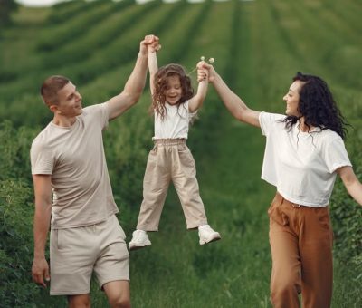 Joyful family moment in a green field during summer, capturing love and playfulness.
